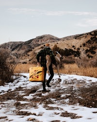 a man carrying a suitcase in the snow