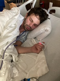 a man is laying in a hospital bed with an electronic device